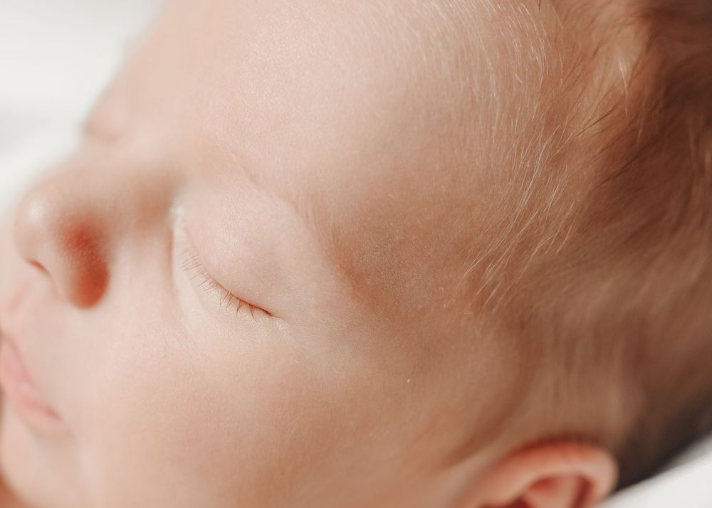Close-up profile of sleeping infant on white bedding.
