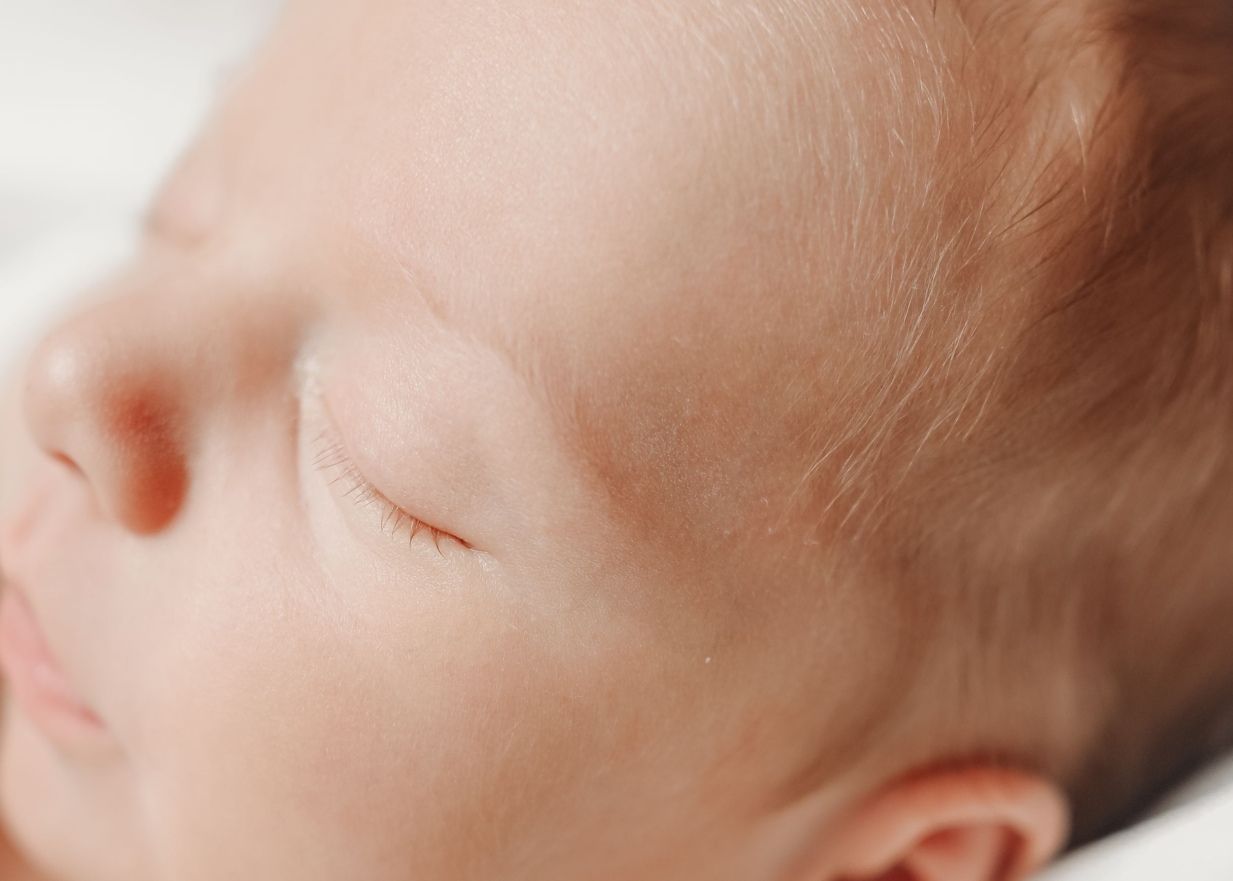 Close-up profile of sleeping infant on white bedding.