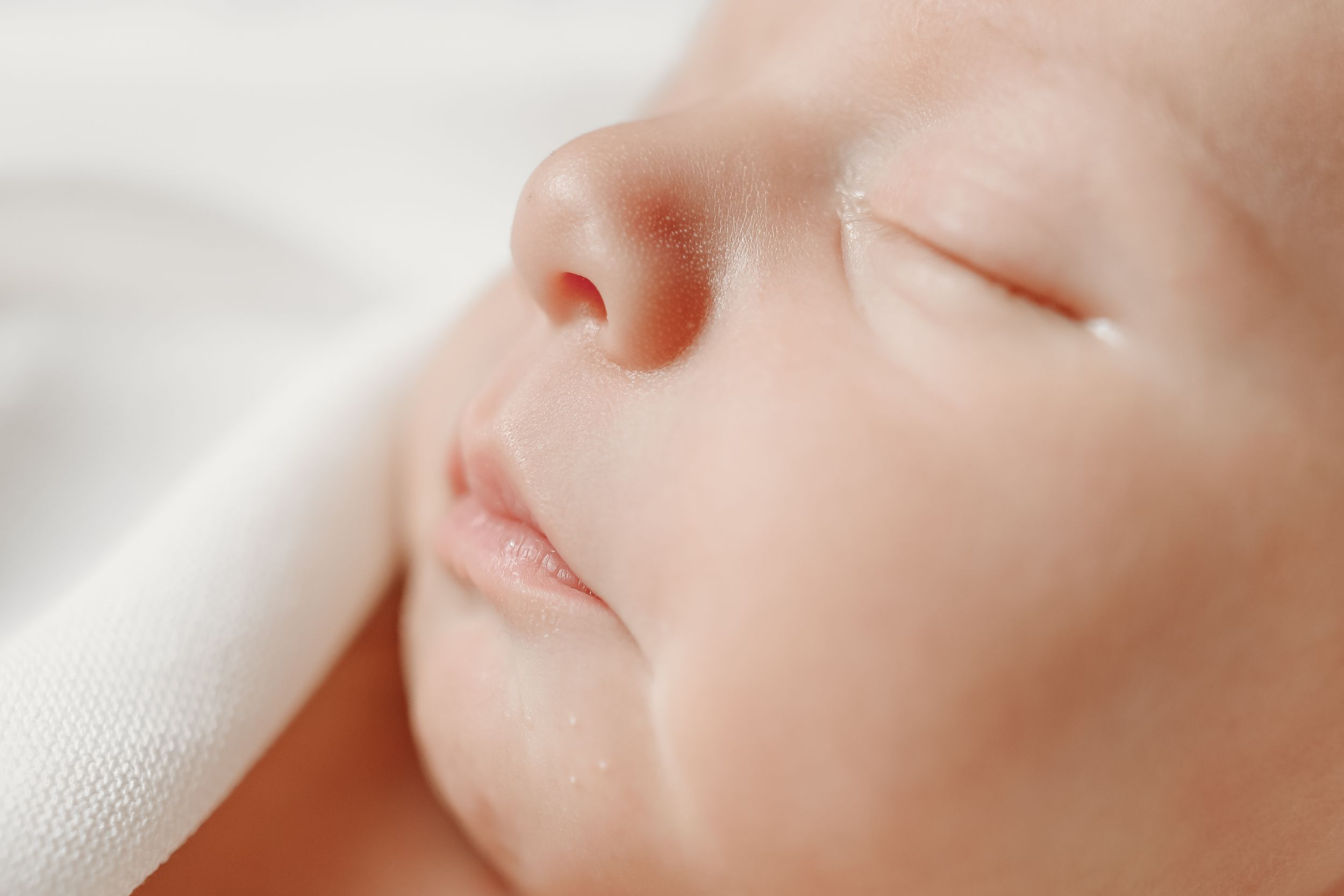 Serene baby sleeping on white textured fabric.