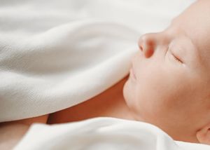 Close-up of white soft cotton fabric or bedding material with gentle folds and creases creating a dreamy texture.