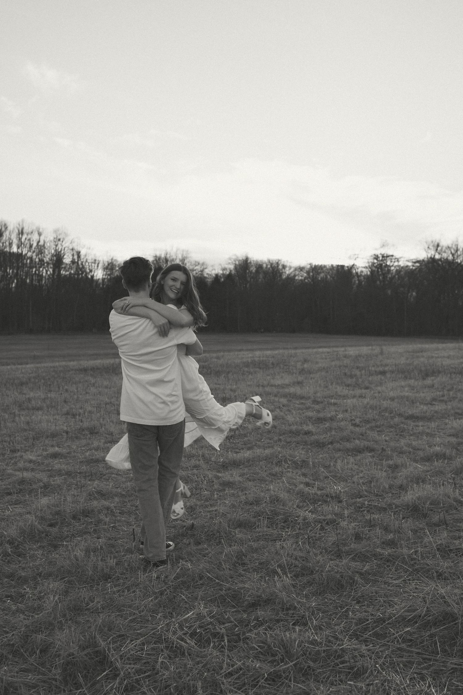 Couple dancing together in an open field at dusk.