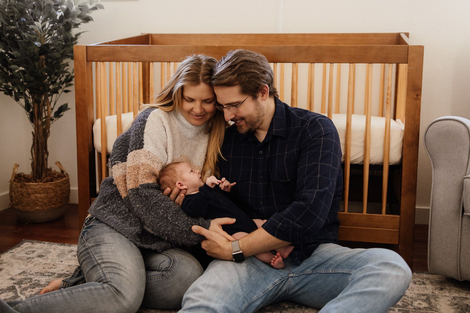 Bay Area newborn photographer captures a heartfelt image of parents cradling their newborn baby in front of his crib in their nursery