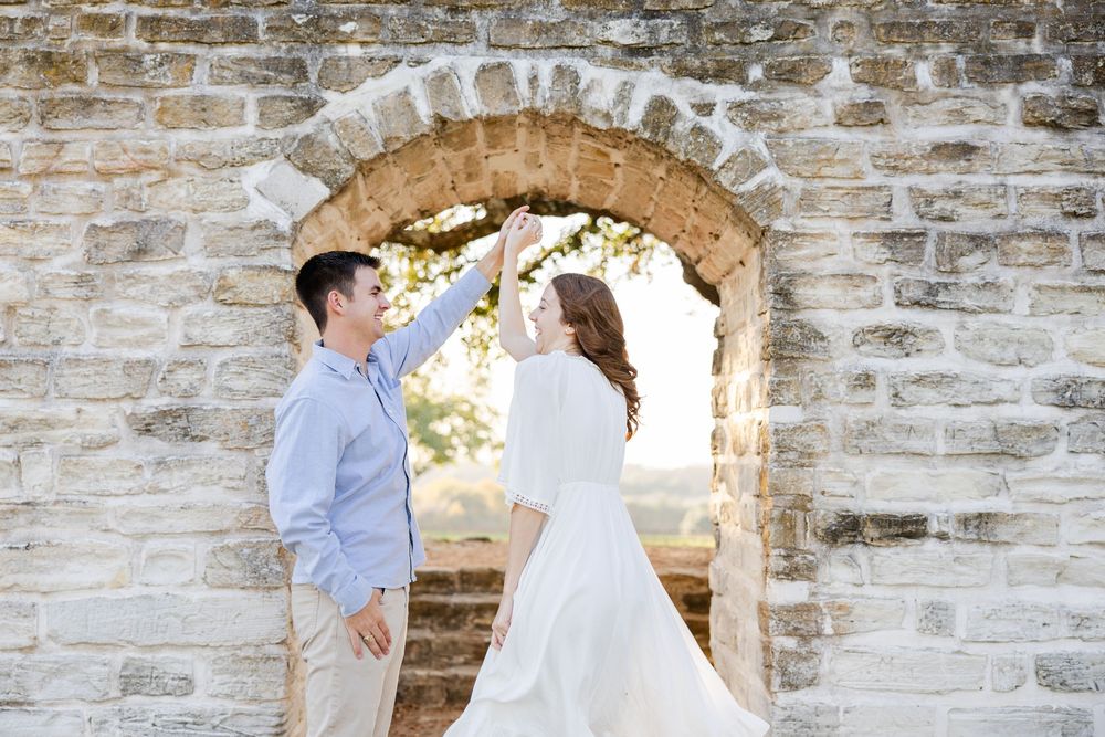 A romantic moment between a couple under a stone archway at an ancient building.