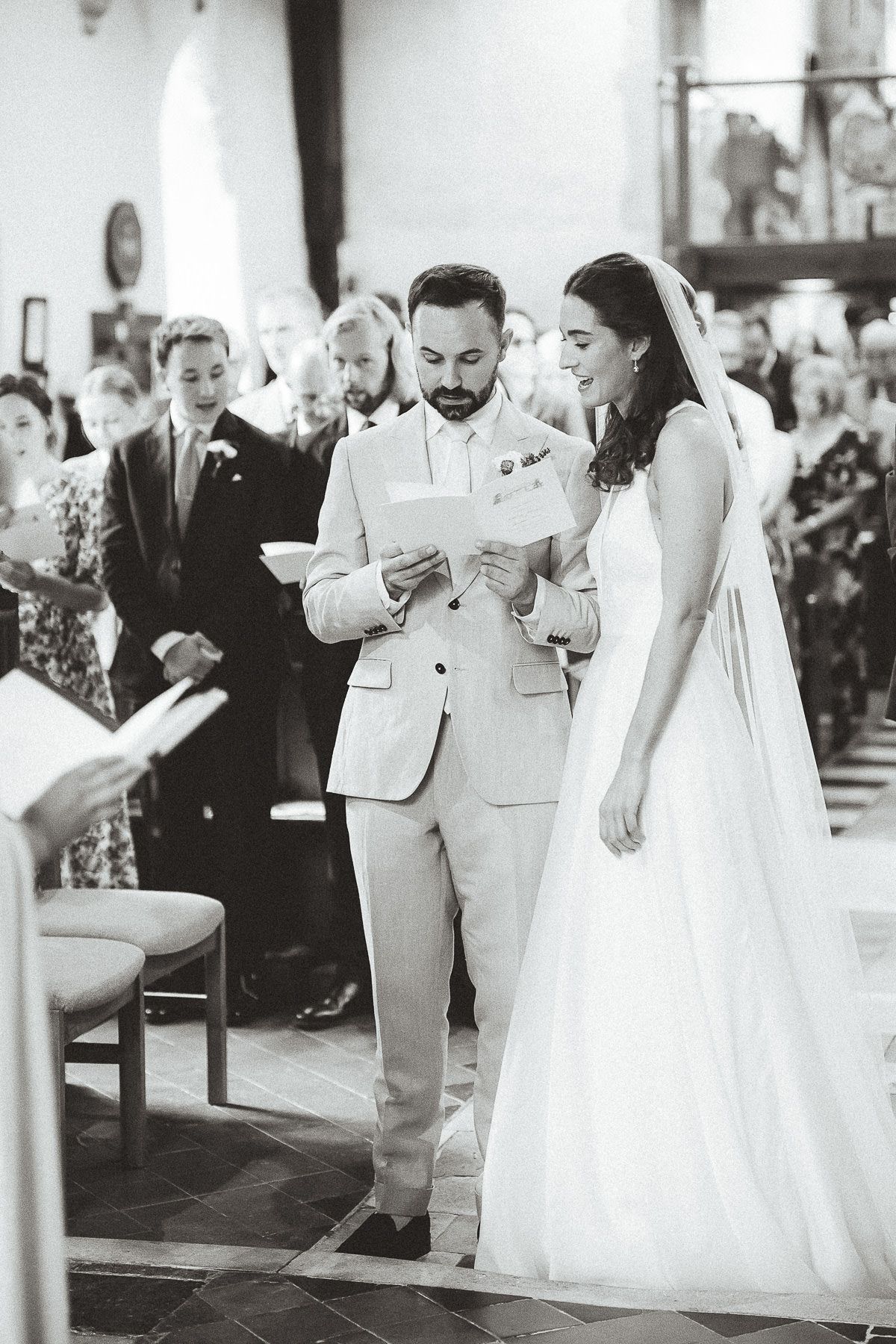 Wedding guests watch as the bride and groom exchange rings during an elegant church ceremony.