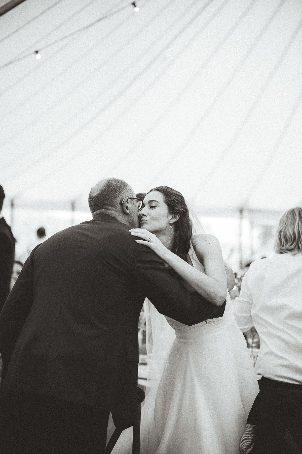 A joyful scene at a wedding reception as a couple shares an emotional moment while seated at a dining table.