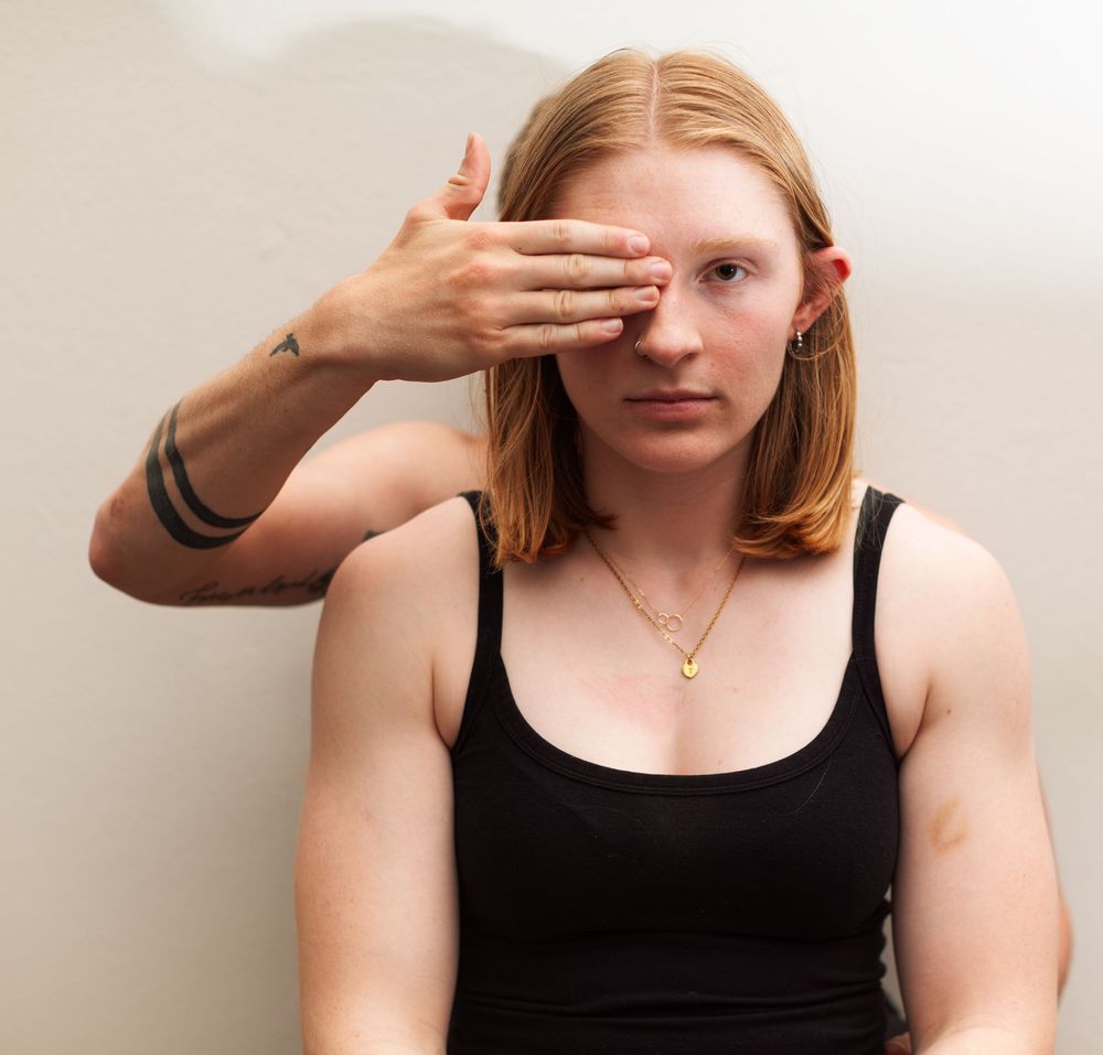 A portrait of a woman with someone else's hand covering part of her face