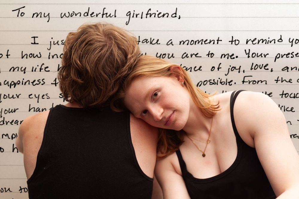 A woman leaning on a man's shoulder with a handwritten letter in the background
