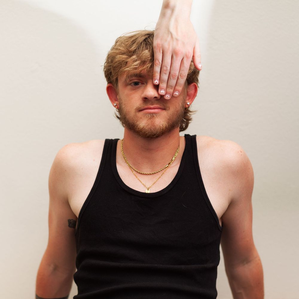 A portrait of a man with a hand covering half of his face