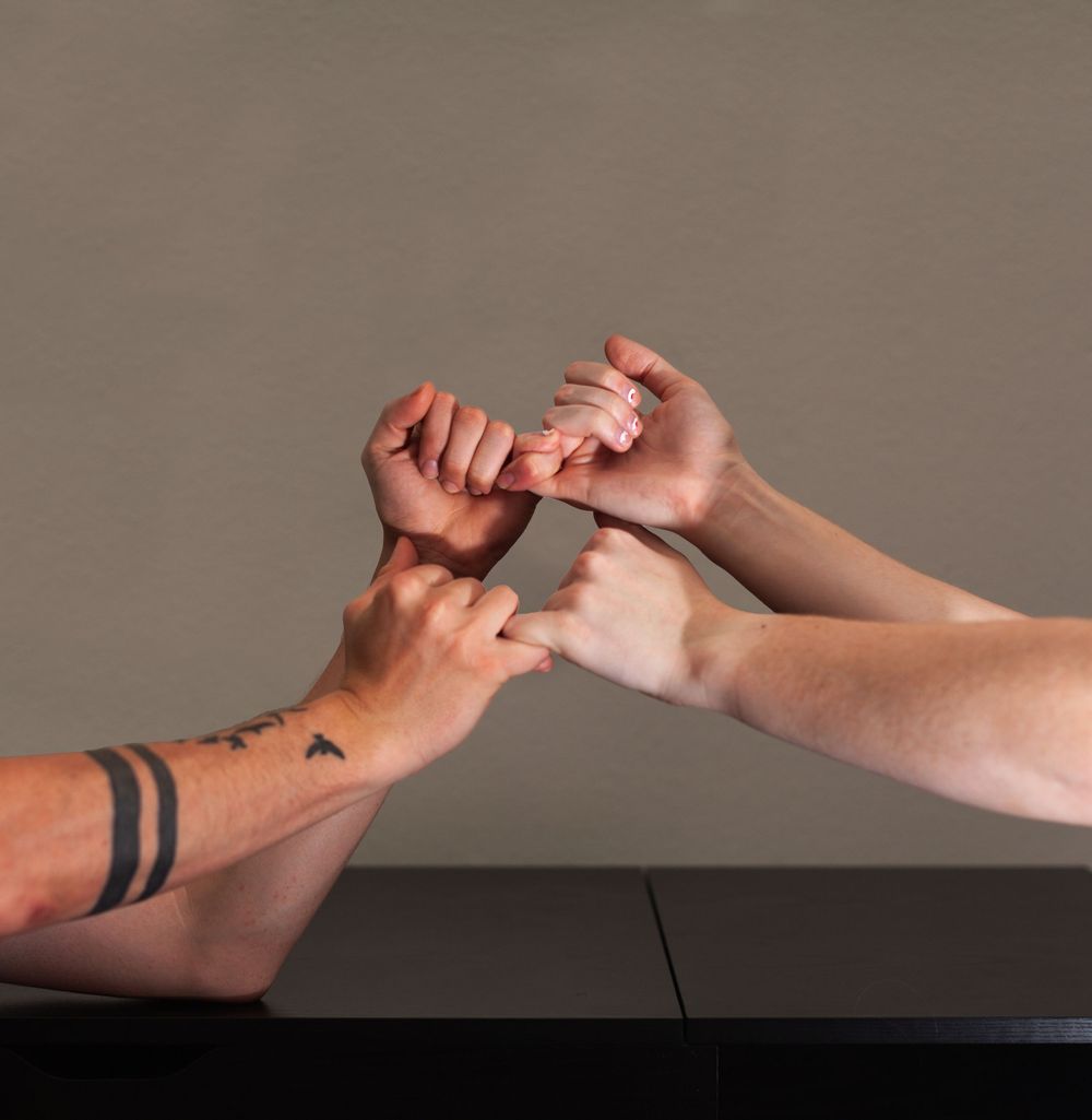Two people intertwining hands in a pinky promise