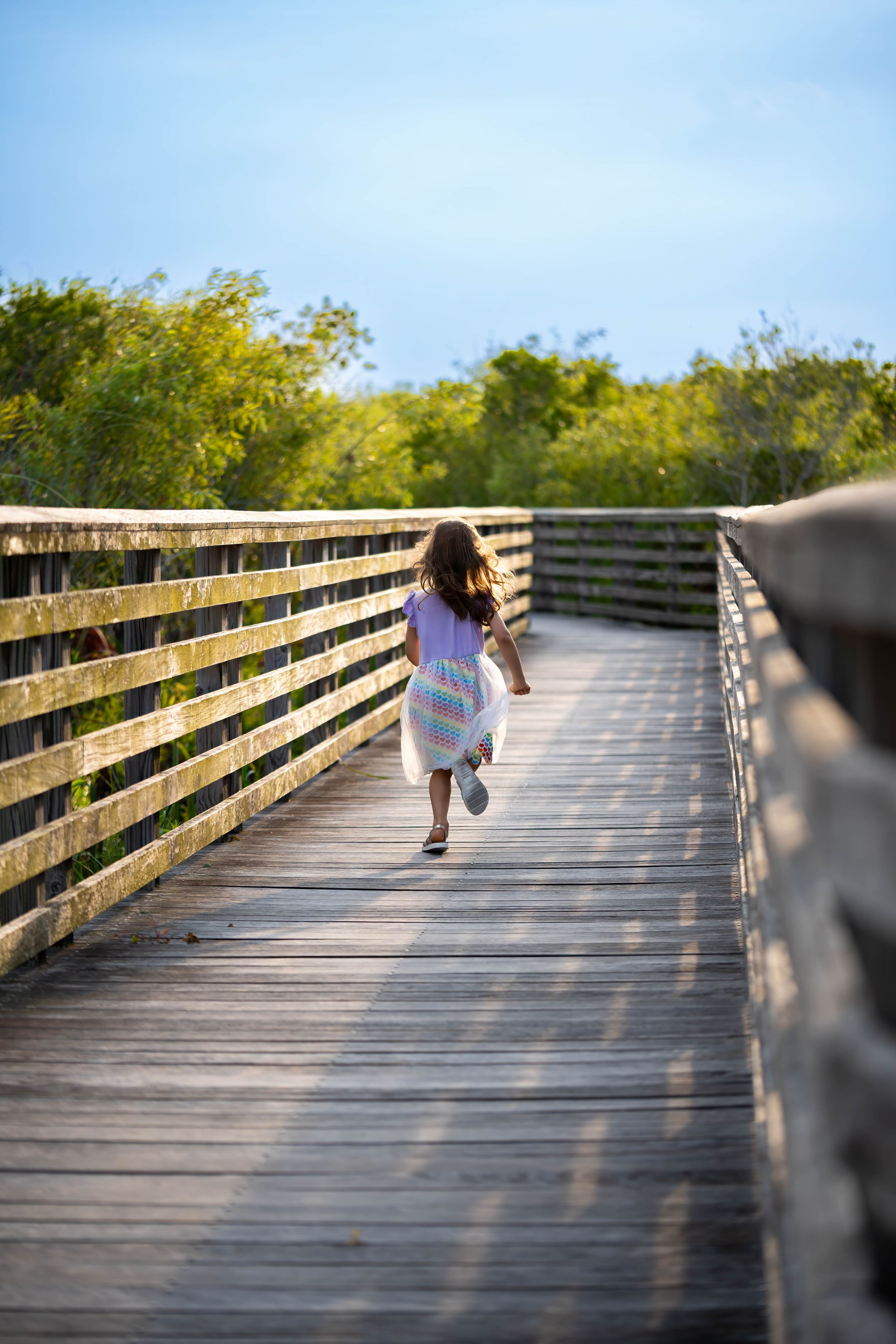 Evelyn playing on the boardwalk during a family session on juno dunes natural area in juno beach florida