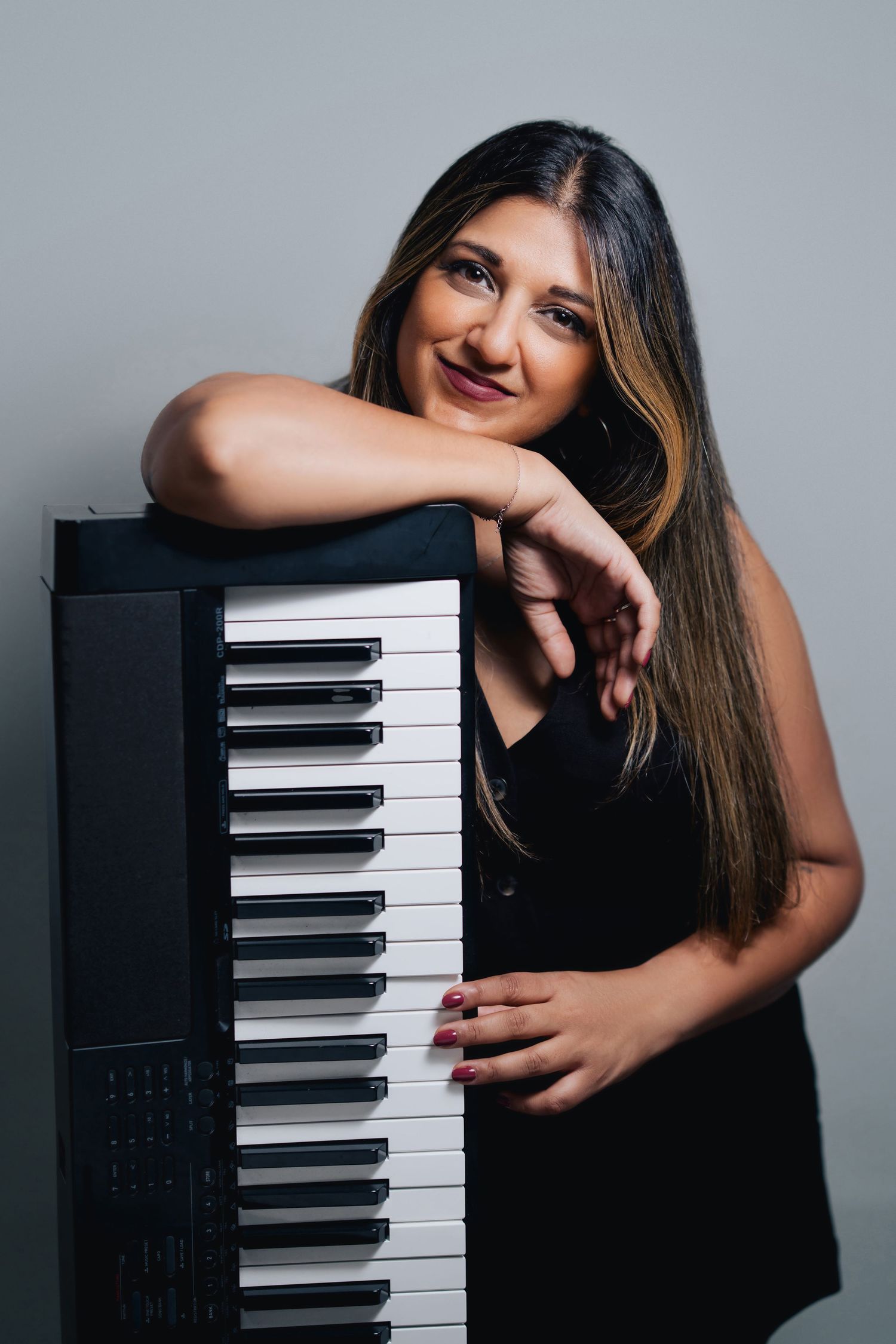 A woman in a black dress poses with a digital piano keyboard in a series of artistic portrait shots.