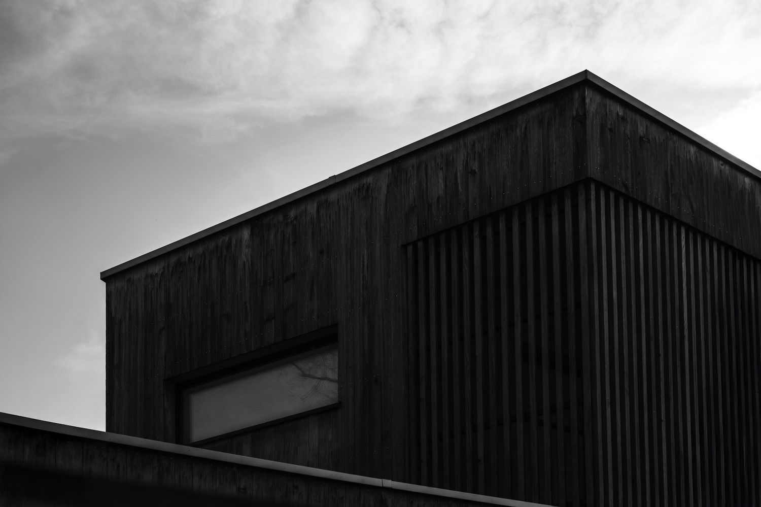 Minimalist architectural silhouettes of industrial buildings against a cloudy sky.