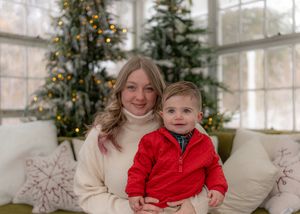 A cozy holiday scene with two people sitting on a white couch in front of a decorated Christmas tree.