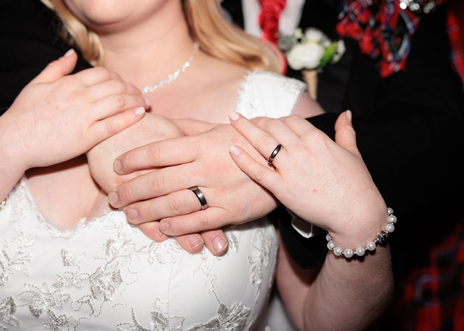 Close-up of hands showing wedding rings and jewelry details.