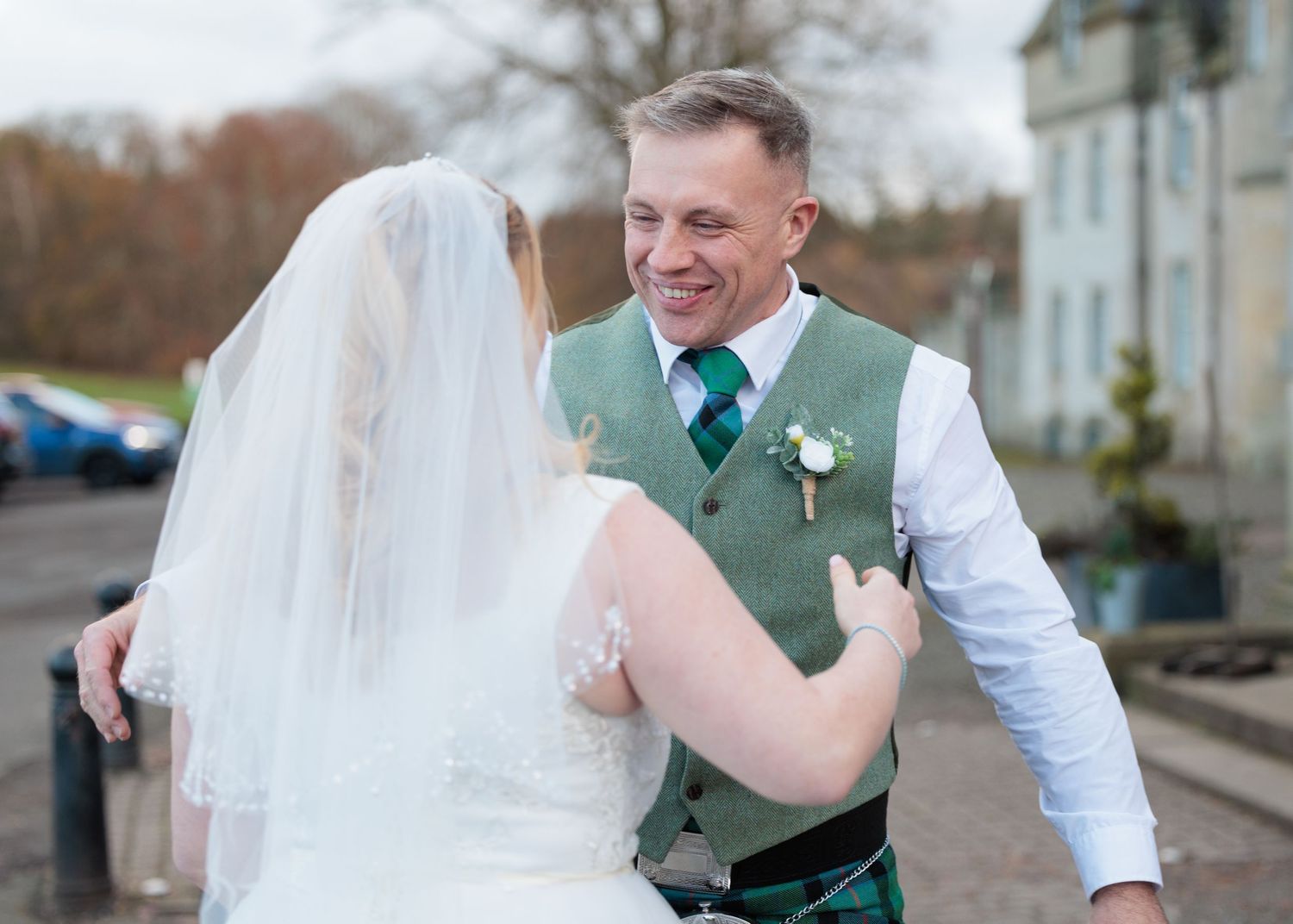 A joyful wedding couple shares a playful moment dancing together outdoors in autumn.
