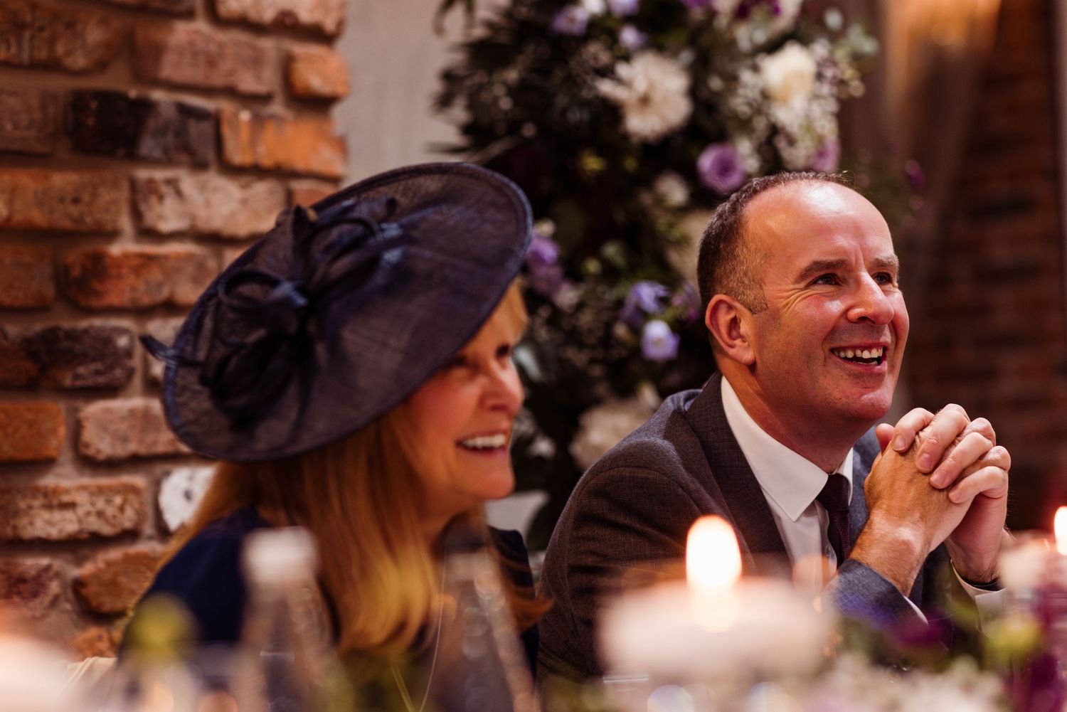 Guests share joyful laughter during an elegant brick-walled reception celebration.
