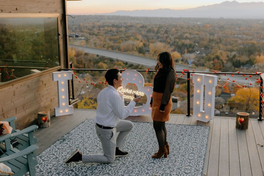A romantic proposal moment on a scenic deck overlooking an autumn mountain landscape at sunset.