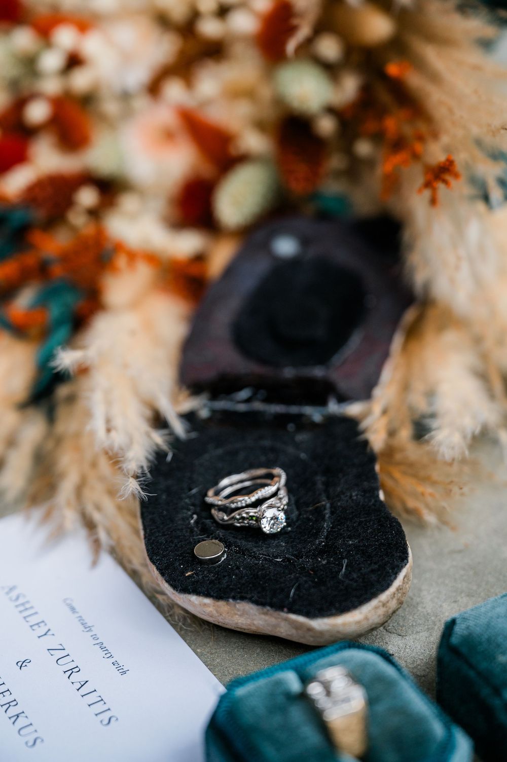 Wedding rings and details photographed with soft focus on dark textured surface.