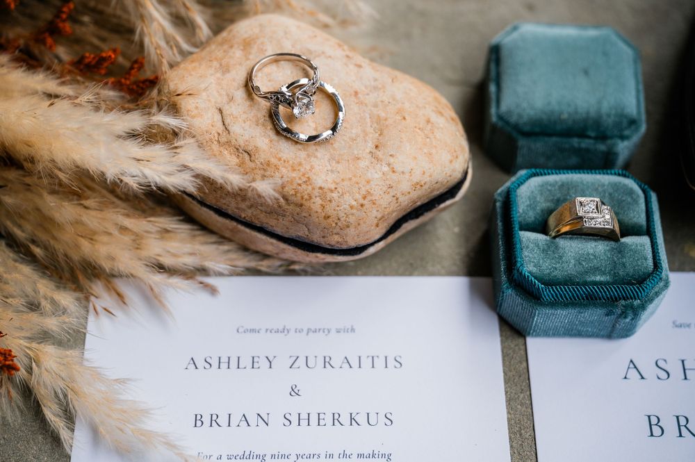 Wedding rings and invitation details in vintage-style teal velvet ring box.