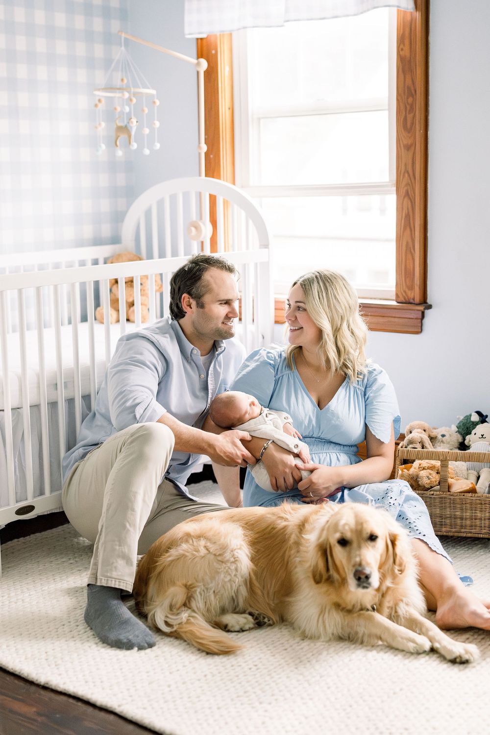 A cozy nursery scene with a golden retriever resting on a carpet near a white crib by a window.