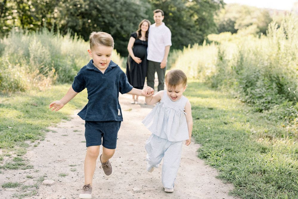 A family enjoys a playful moment walking together on a nature path during golden hour.
