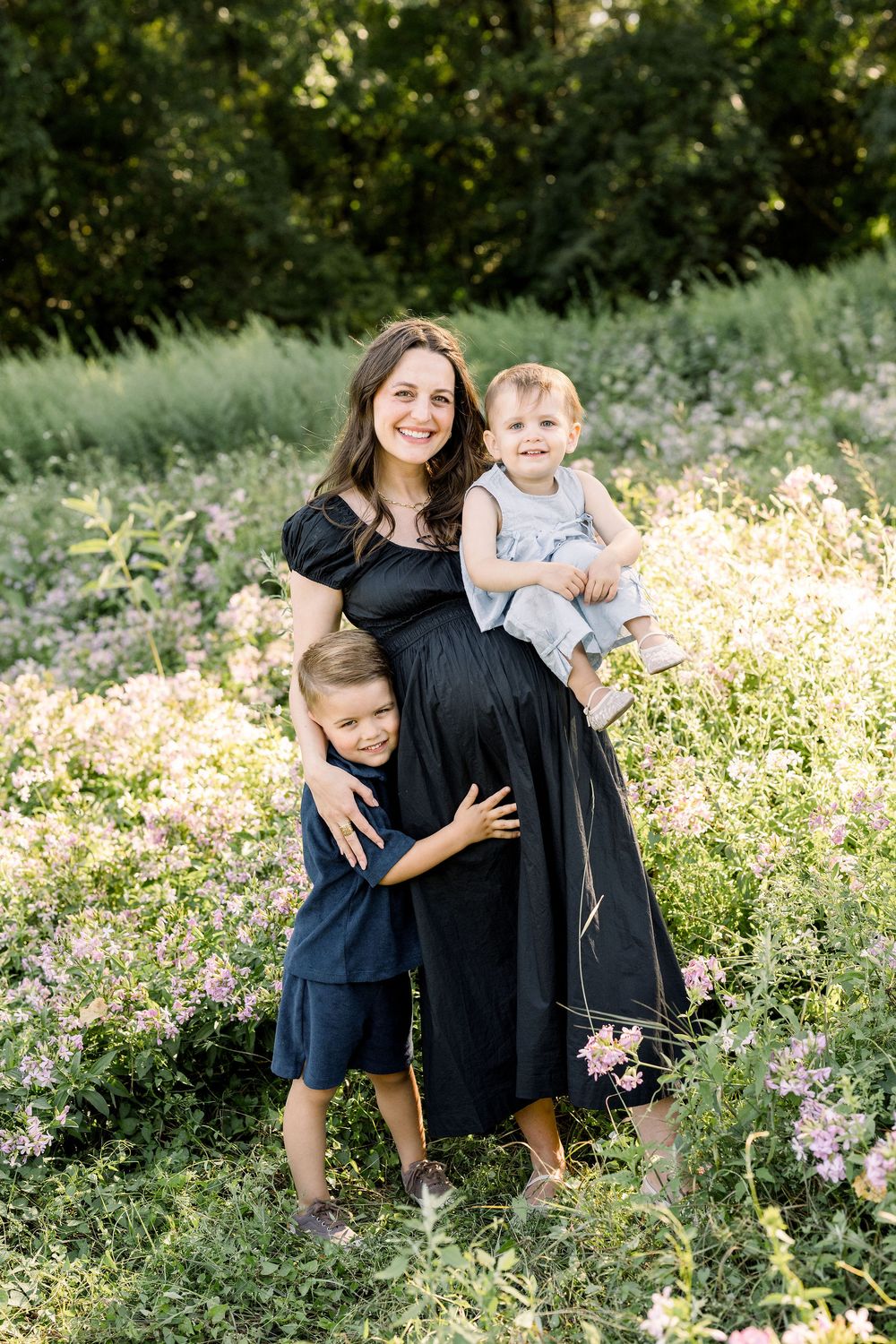 Family members share joyful moments together in a field with wildflowers and natural greenery.