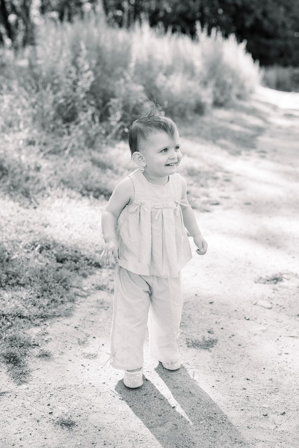 A series of vintage black and white photographs showing a toddler in a light-colored outfit walking on a dirt path.