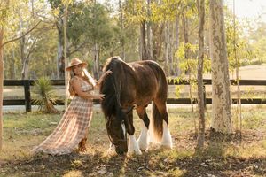 A panoramic view shows horse and rider on a wooded trail during golden hour at a ranch in a special horse photoshoot in sydney