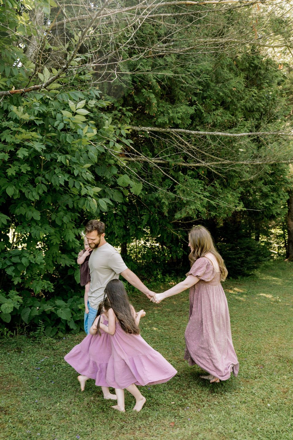 Two figures in pink dresses dance and twirl playfully together in a sunlit garden setting.