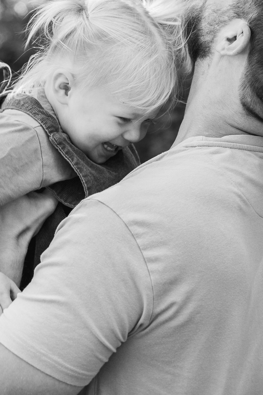 A black and white intimate portrait showing a joyful moment of laughter and closeness between parent and child.