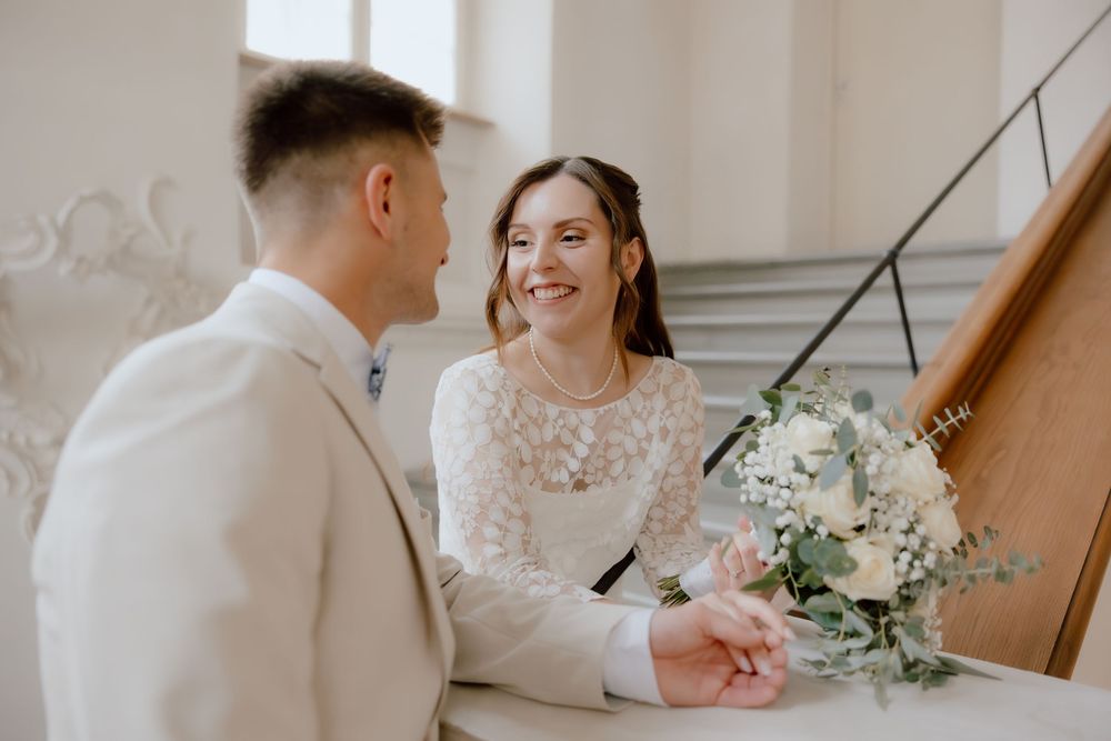 A bride and groom share intimate moments during their wedding photoshoot in a light-filled stairwell.