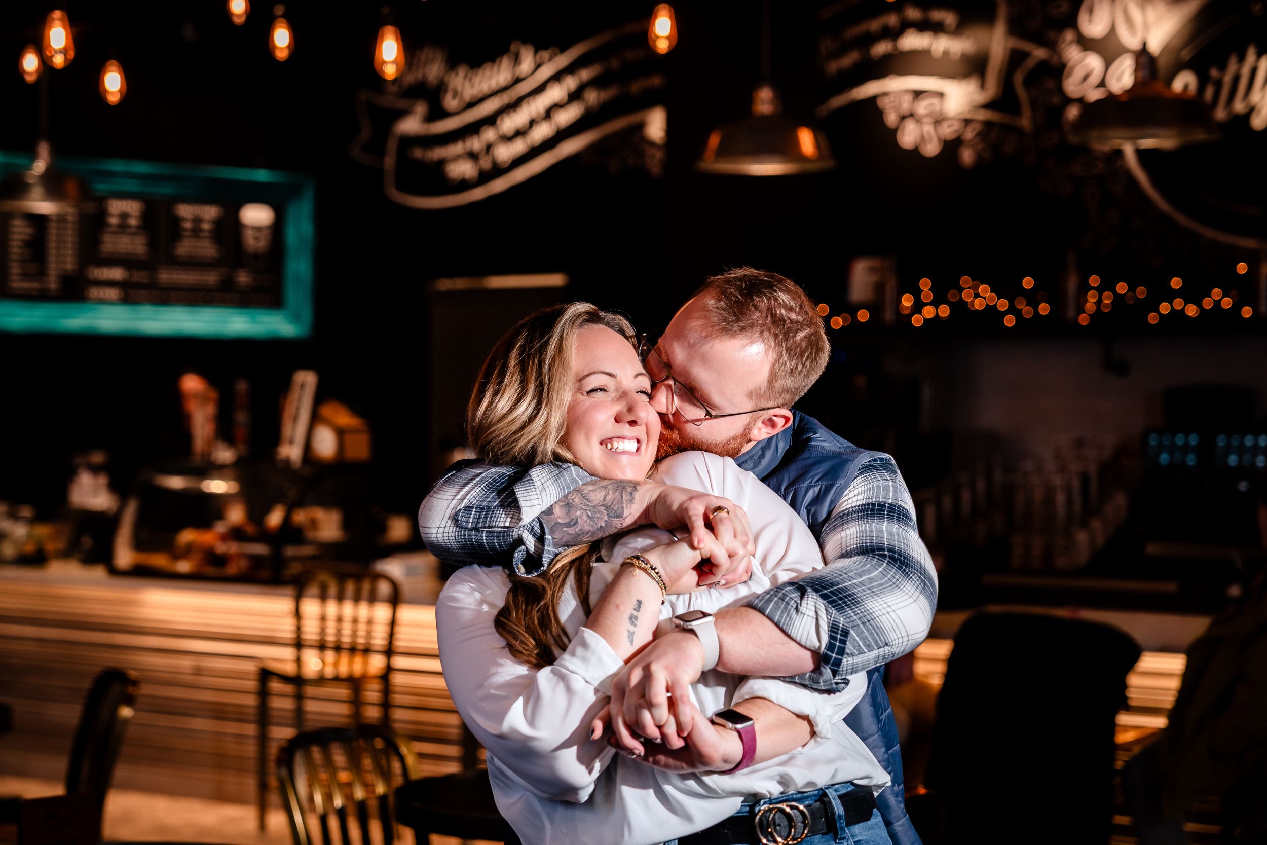 Romantic couple sharing intimate moments in a dimly lit restaurant with warm glowing lanterns overhead.
