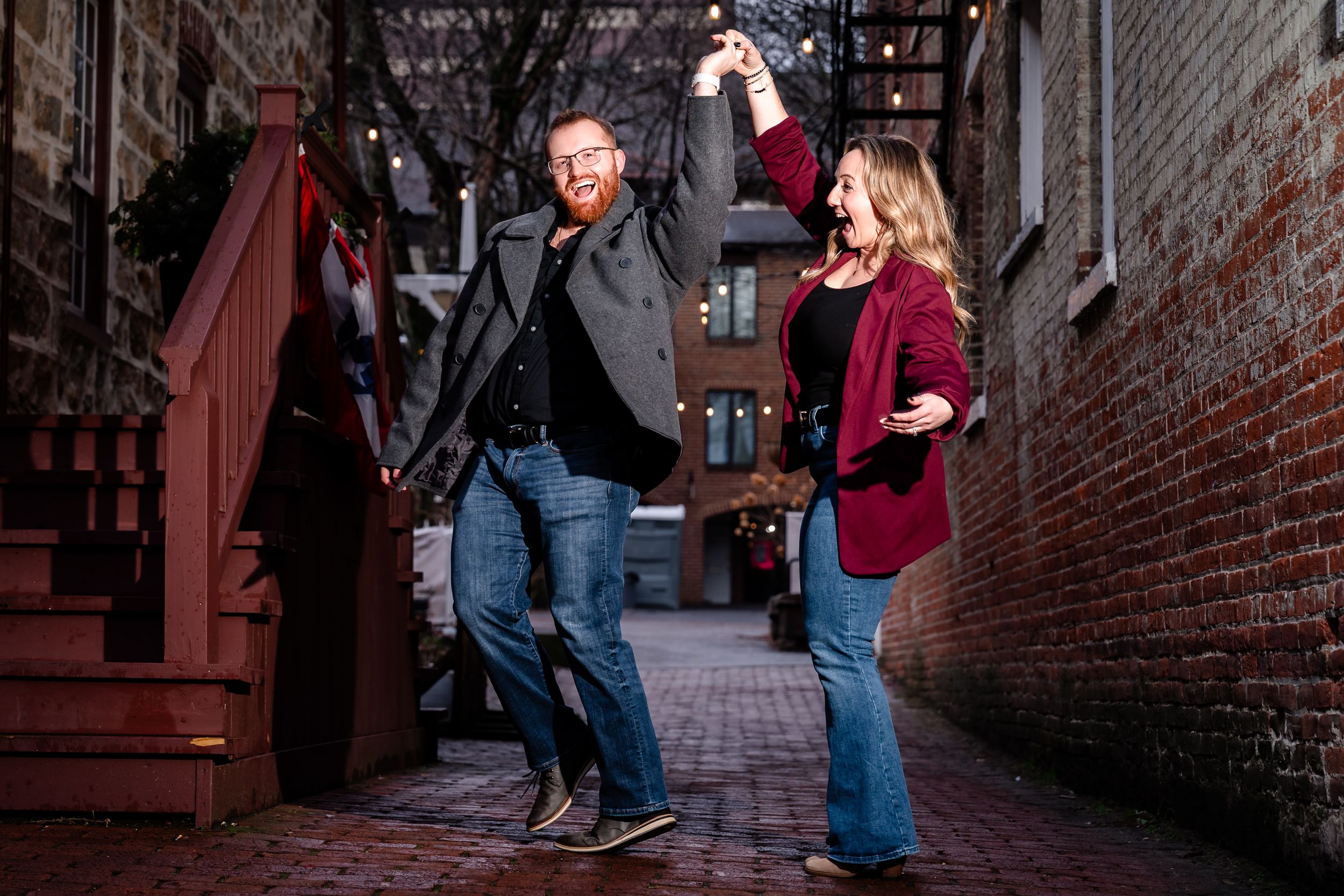 A couple poses for romantic photos in an urban brick alleyway setting.