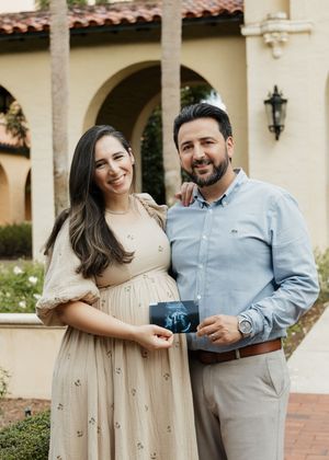 A couple shares a romantic moment together in a Spanish-style courtyard setting with arched walkways and brick paths.