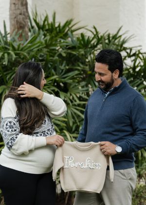 A couple embracing while wearing coordinating navy blue and cream colored sweaters outdoors.