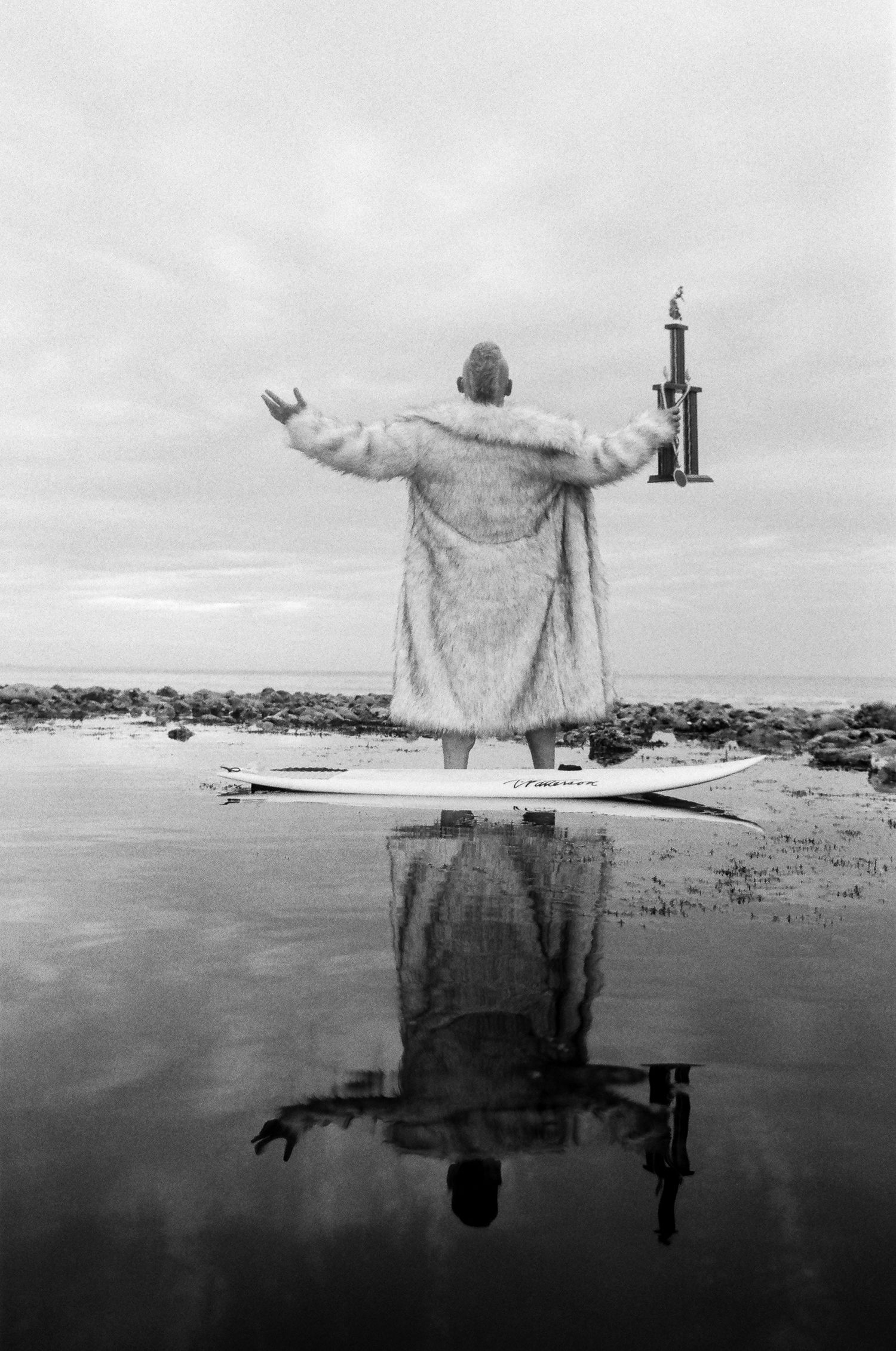 A black and white photo series shows a person standing in water with arms outstretched, creating a reflection below.