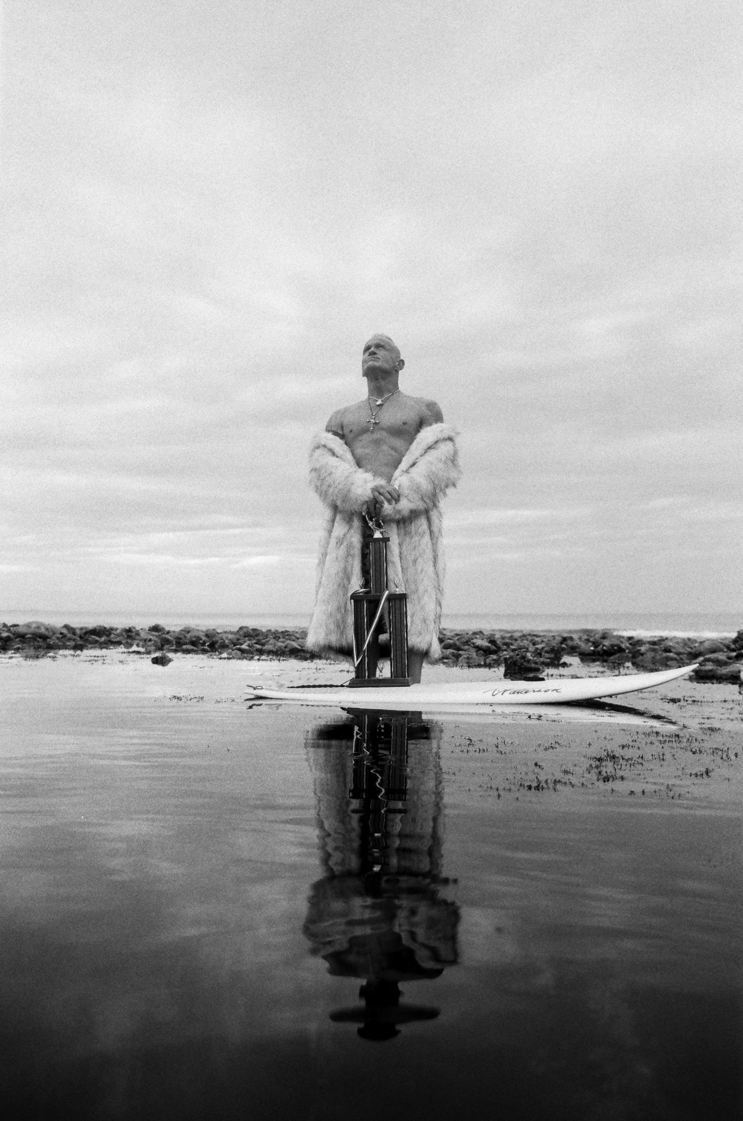 A series of black and white photos showing a person with angel wings reflected in calm water at the beach.