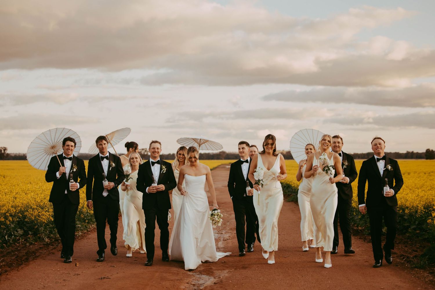 Wedding party walking through a scenic field at sunset.