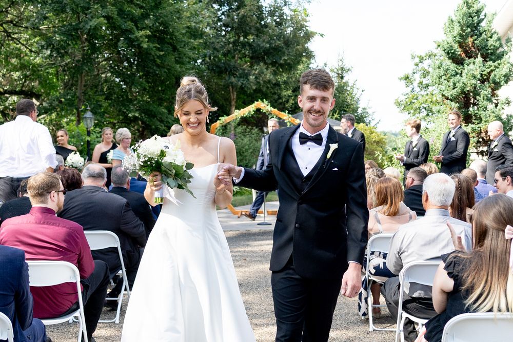 Wedding guests celebrate during outdoor reception with dancing and socializing in garden setting.