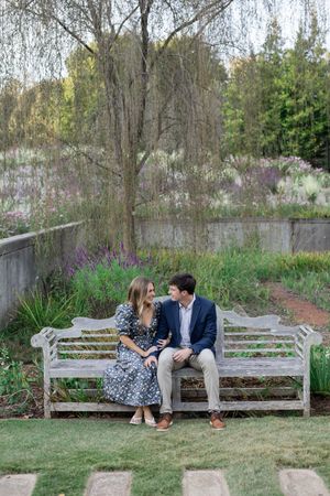 Couple sharing tender moments on a park bench surrounded by spring flowers.