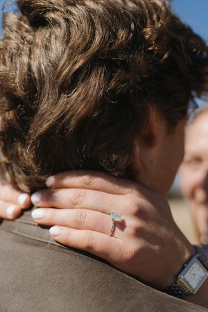 Close-up of hands embracing showing engagement ring and watch details.