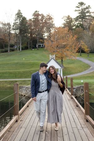 Couple sharing romantic moments on a wooden bridge in an autumn park setting.