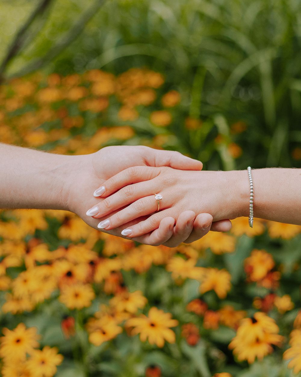 Sequence of hands reaching and touching with orange flowers in the background.
