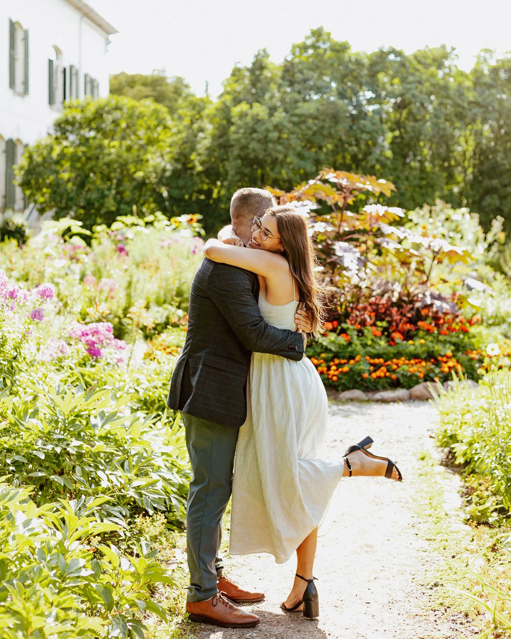Couple sharing a romantic moment in a blooming garden path surrounded by colorful flowers.