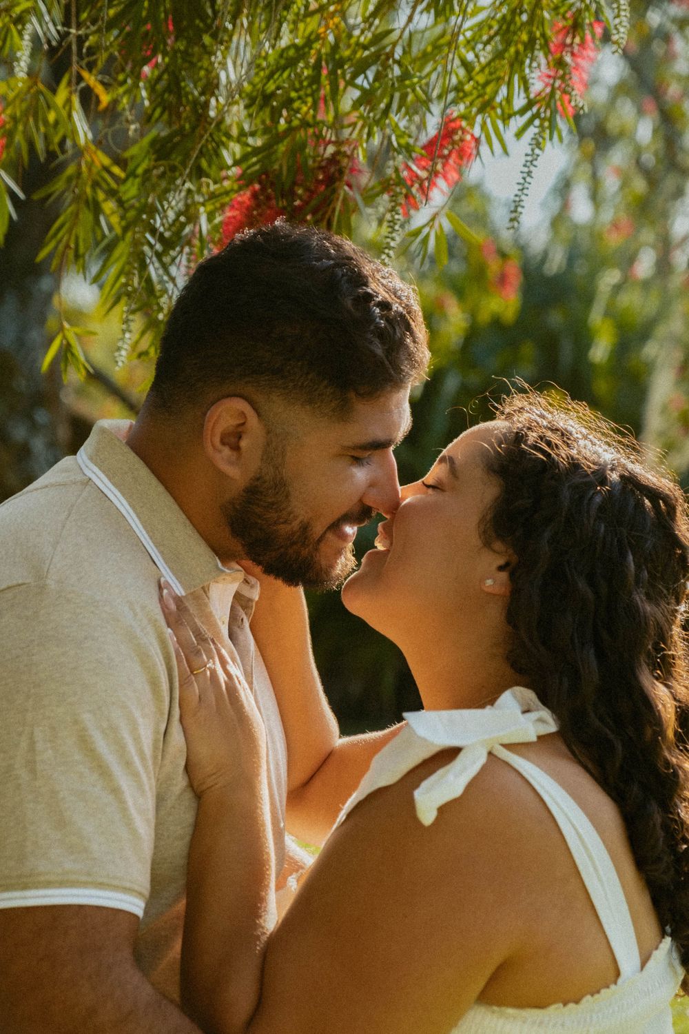 A tender moment between a couple under flowering trees with red blooms.