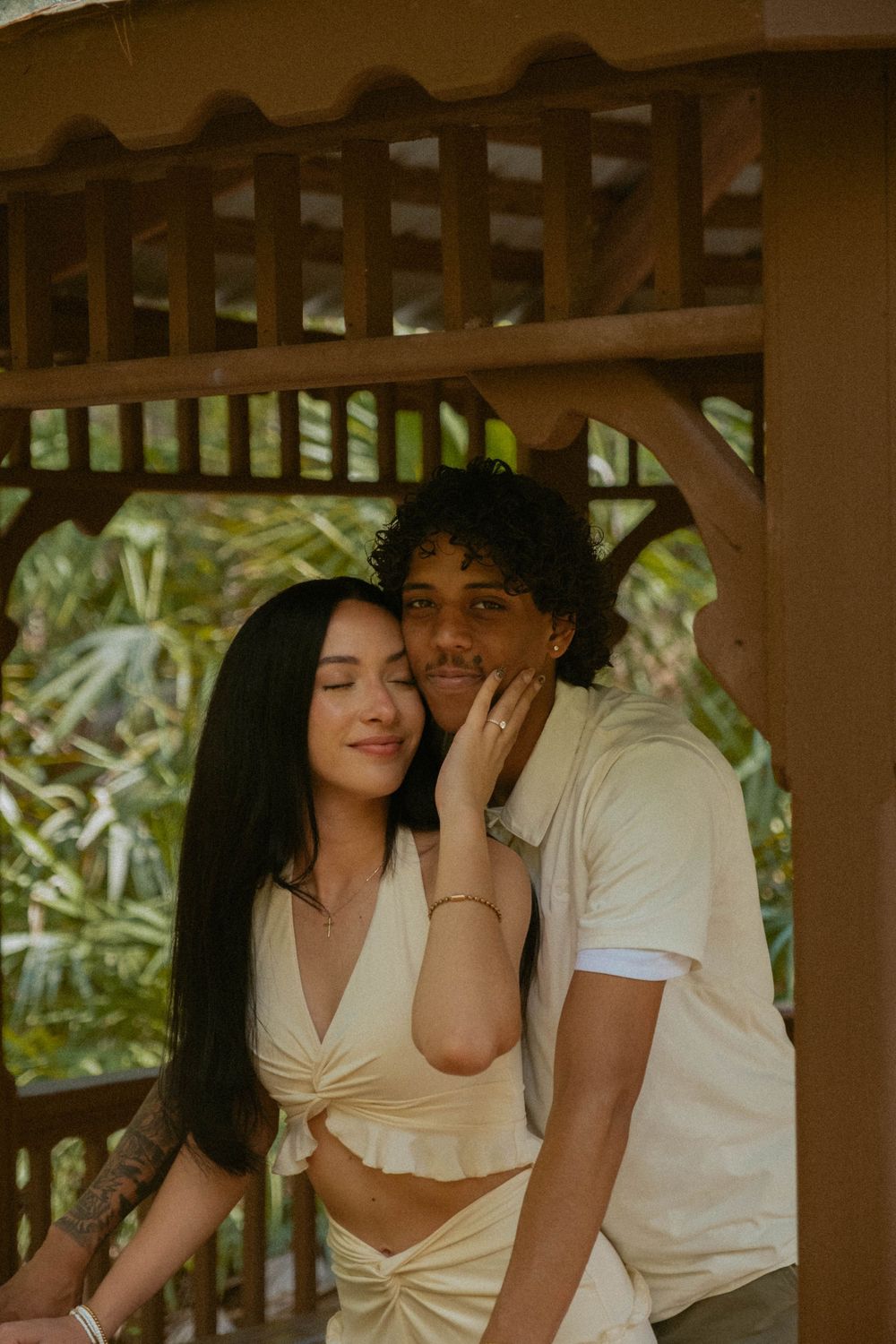 A romantic scene captured in a wooden gazebo with natural lighting.
