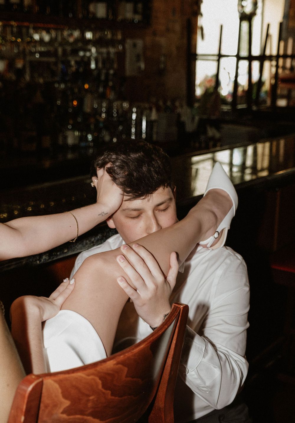 A romantic scene unfolds in a cozy bar interior with warm ambient lighting.