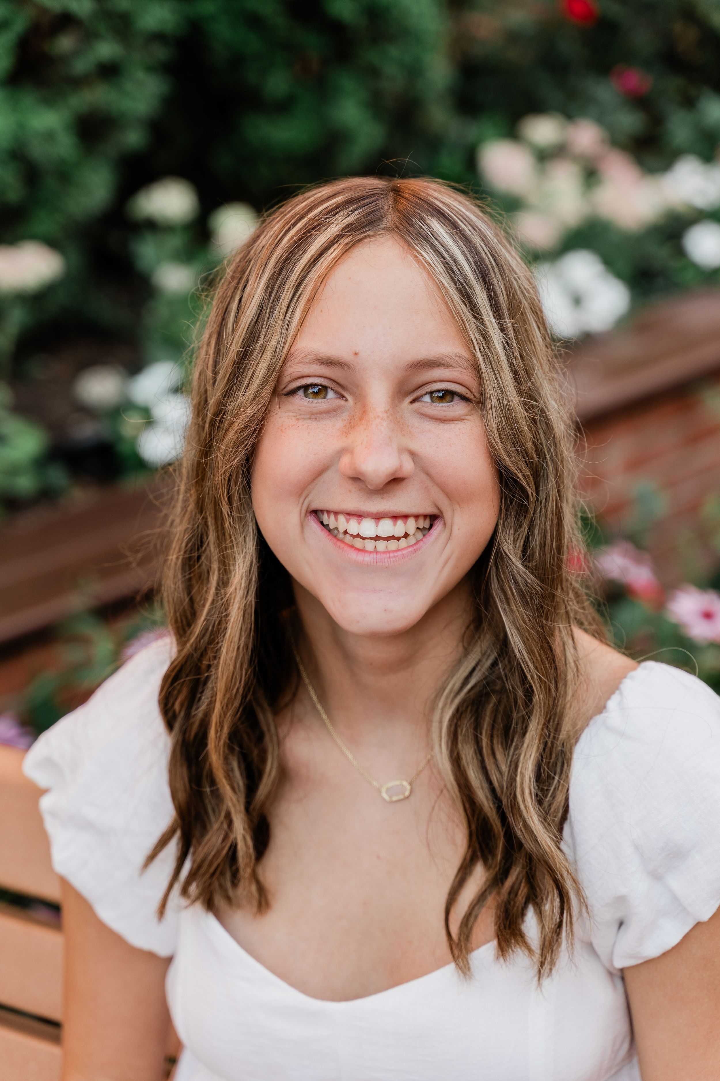 A series of four similar portraits showing a person with brown hair wearing a white top smiling outdoors.