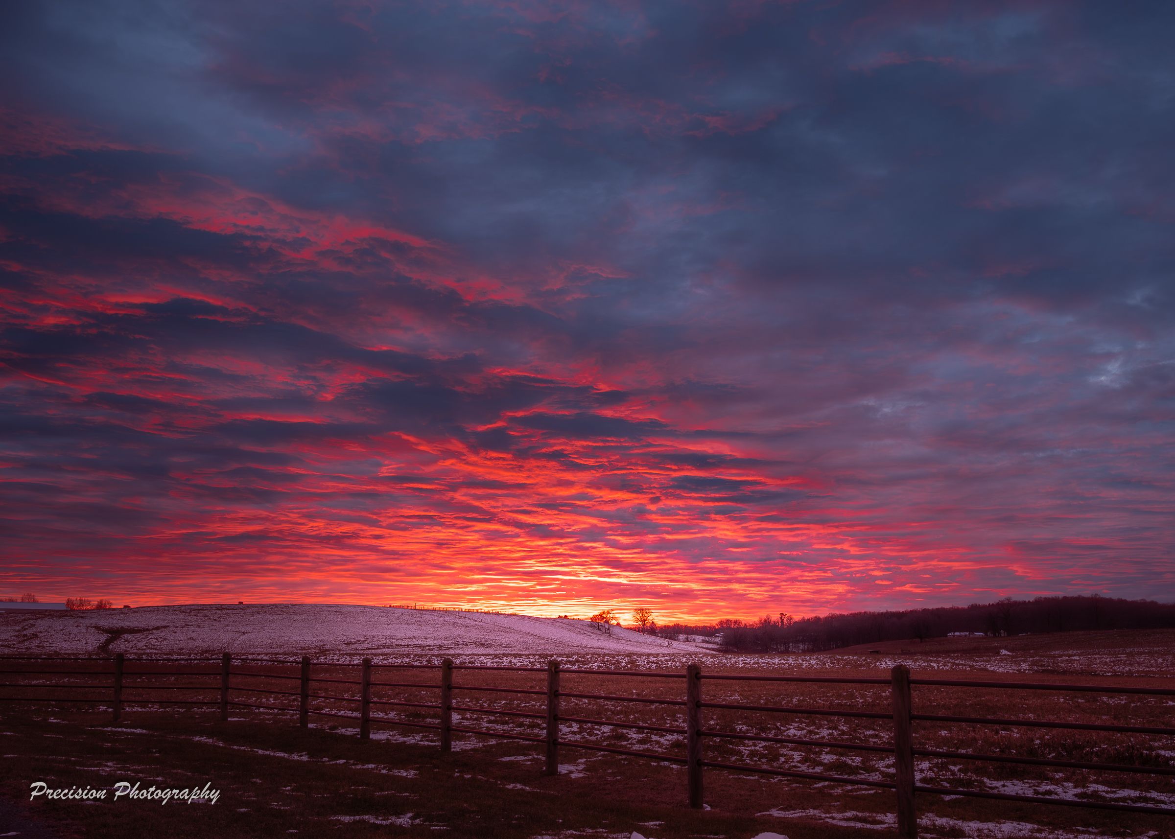 A dramatic time-lapse sequence of a vibrant red and purple sunset over a rural landscape with silhouetted hills.