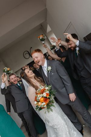 Wedding party celebrates with animated expressions and gestures.